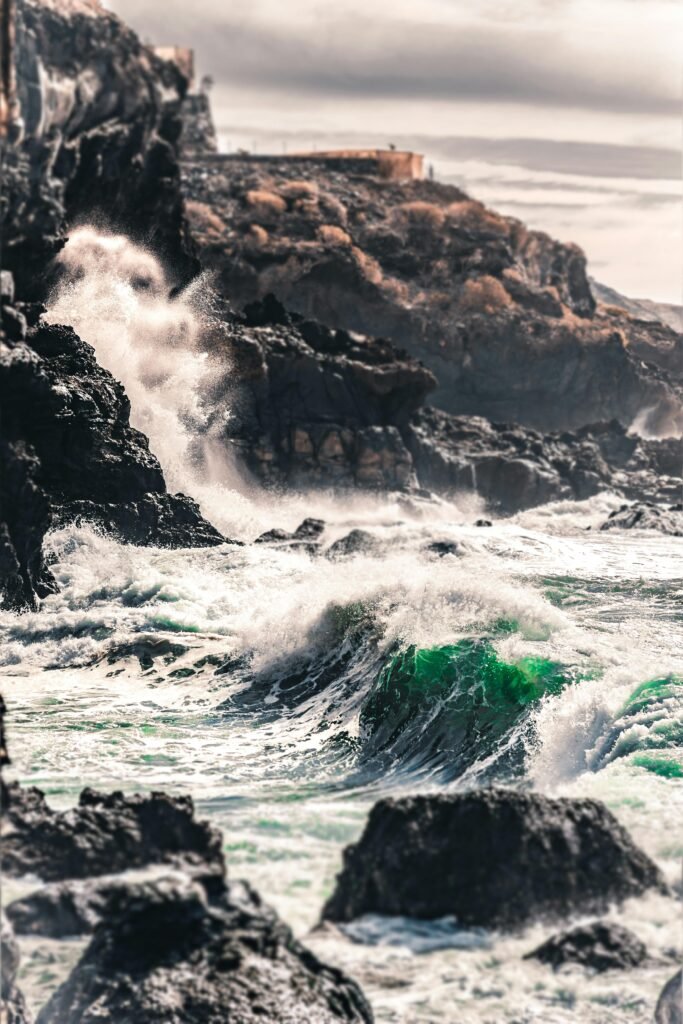 Powerful ocean waves crashing against rocky cliffs on Playa San Juan's coast in Spain.