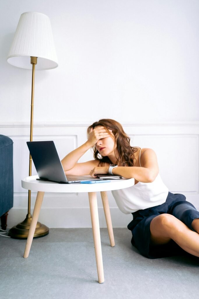 A woman showing signs of fatigue while working remotely at a laptop indoors.